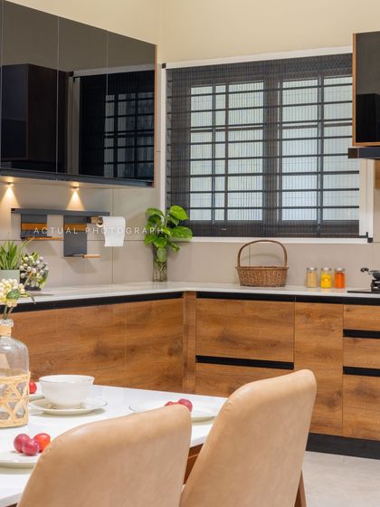 This kitchen and dining area combines sleek black upper cabinets with warm wood-textured lower units. The design creates a beautiful contrast while maintaining an open and inviting feel.