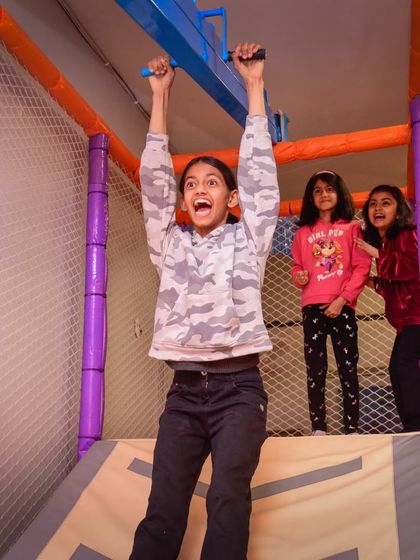The look of triumph! This girl feels on top of the world as she zips across our monkey bars with her friends cheering her on.