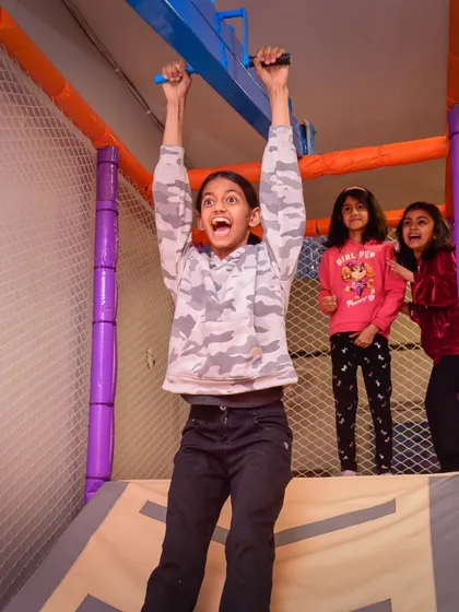 The look of triumph! This girl feels on top of the world as she zips across our monkey bars with her friends cheering her on.
