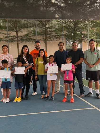 Young players pose with their families, coaches, and certificates after a successful tournament weekend. We foster a strong community where parents and coaches work together to support our athletes.