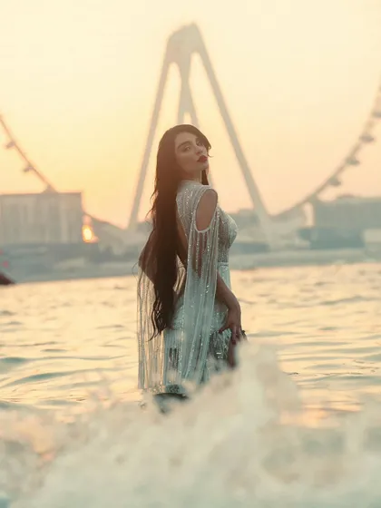 A dreamy, soft-focus portrait of a woman in the sea at sunset. The waves and golden light create a magical and ethereal atmosphere.