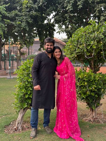 A Karwa Chauth photo with my husband. I'm wearing a bright pink floral saree, offering a different style option for the festival that is both traditional and vibrant.