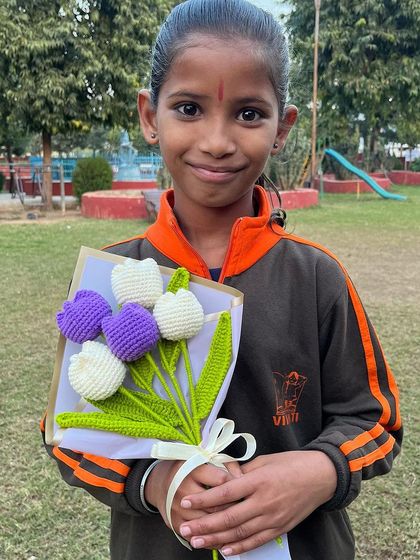 The simple joy of a handmade gift. A young girl holds our 'Lilac Love' bouquet, a beautiful mix of purple and white crochet tulips.