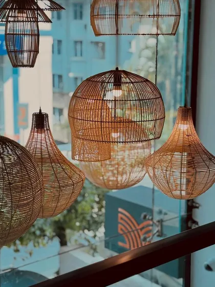 Detail of our hand-woven rattan light fixtures. These artisanal pieces cast a soft, warm light throughout the dining room, contributing to the cozy and natural aesthetic of the space.