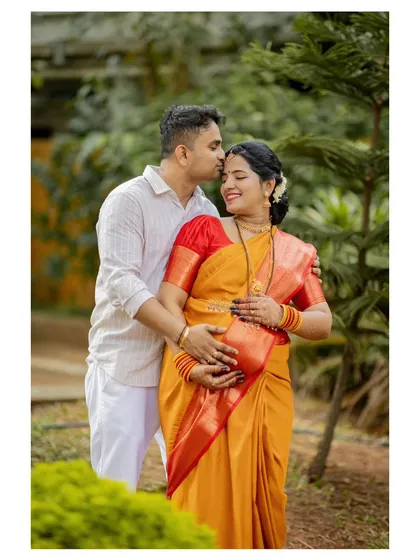 An intimate moment during an outdoor maternity photoshoot. We find that natural, green settings in places like Mangalore and Udupi help couples relax, allowing us to capture genuine affection and anticipation.