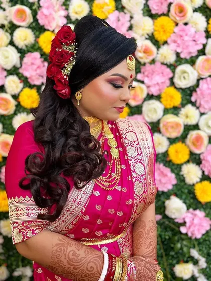 This side profile showcases the elegant bridal hairstyle, adorned with fresh red roses, and the flawless blending of her reception makeup. The look is both traditional and glamorous.