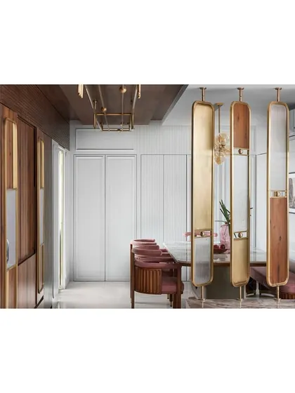 The dining area is separated from the living space by four elegant panels of wood, glass, and brass. This creates a sense of separation while maintaining the illusion of a larger, grander space.