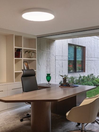 A director's cabin in 'The Layered Office' with a large window overlooking the landscaped grounds. The minimalist design focuses on clean lines and high-quality materials, creating a serene and focused workspace.