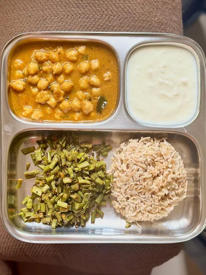 A simple meal of brown rice, channa masala, sautéed beans, and curd. This is a classic, easy-to-make, and nutritious lunch.