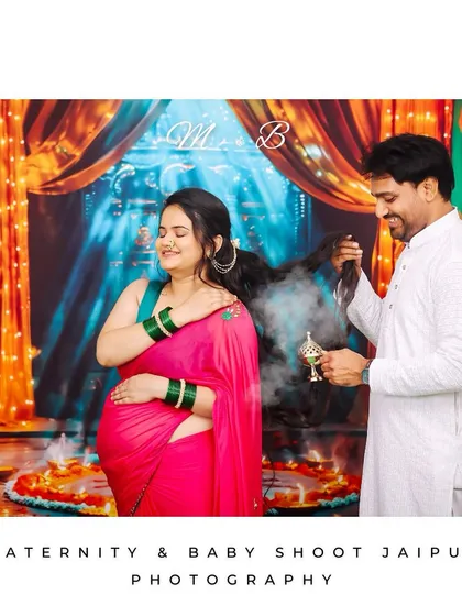 A unique and culturally rich maternity photoshoot embracing tradition. The expecting mother is in a beautiful saree, creating a timeless and personal portrait in a festive studio setting.