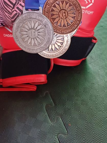 A close-up of the hard-earned medals from the kickboxing nationals, resting on a pair of boxing gloves.
