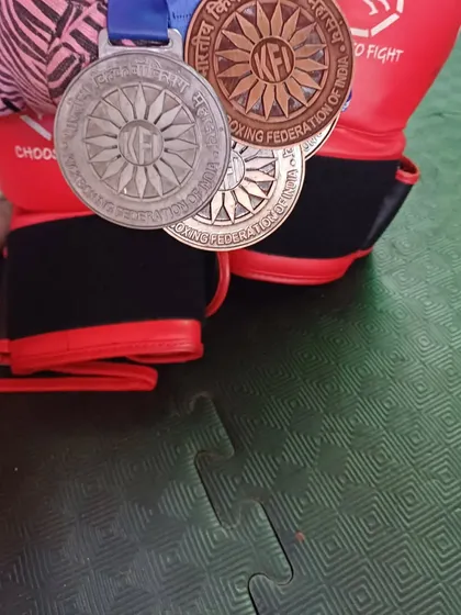 A close-up of the hard-earned medals from the kickboxing nationals, resting on a pair of boxing gloves.