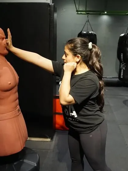 A female student practices a palm-heel strike on a training dummy. We drill these fundamental moves until they become second nature, ensuring you can perform them under pressure without hesitation.