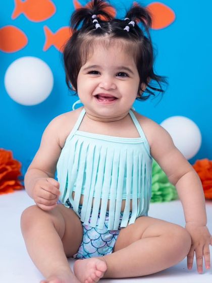 A beautiful, happy portrait before the cake smash begins. Her smile and the colorful setup promise a fun session ahead.