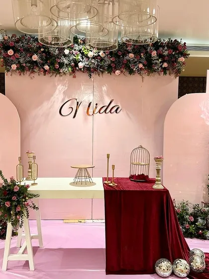 A full view of Nida's pretty-in-pink birthday party. The setup included a large custom backdrop, oversized paper flowers, and elegant floral arrangements in shades of pink and burgundy.