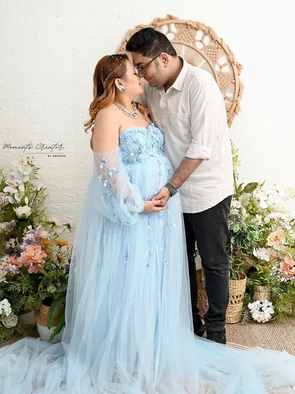 A soft and romantic moment between the expecting parents. This shot, set against a bright floral backdrop, highlights the joy and tenderness of this special time.