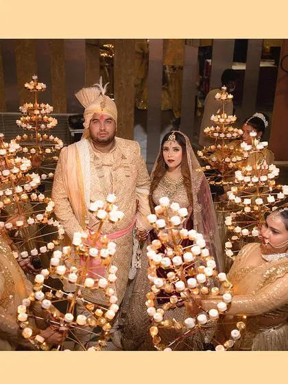 A royal wedding portrait of the couple, framed by attendants holding beautiful candle arrangements. This shot creates a magical and grand atmosphere for their entry.