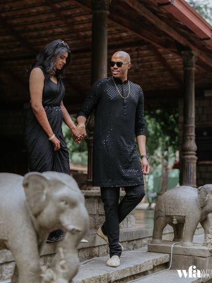 A stylish couple walks down the stone steps, hand in hand, flanked by our signature elephant statues.