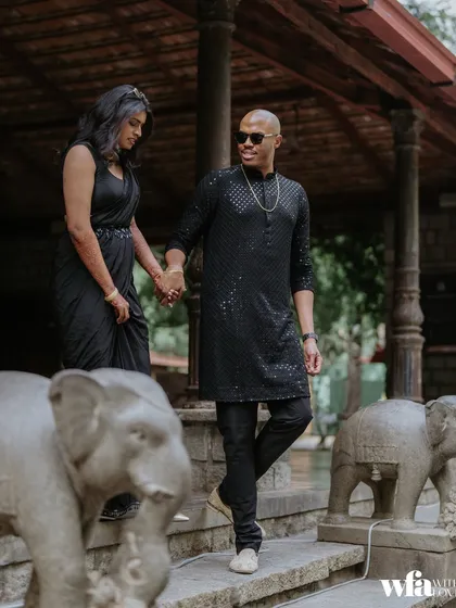 A stylish couple walks down the stone steps, hand in hand, flanked by our signature elephant statues.