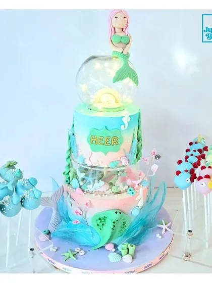 Here is one of my favorite mermaid-themed dessert tables. The centerpiece is a stunning three-tiered cake with an illuminated globe, surrounded by matching under-the-sea cakepops. I can create a complete, coordinated look for your event.