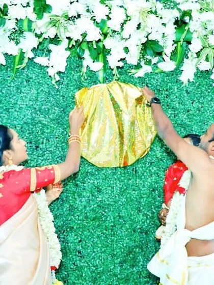 The moment of the name reveal. The parents unveil the baby's name, which was hidden behind a golden cloth on the greenery backdrop.