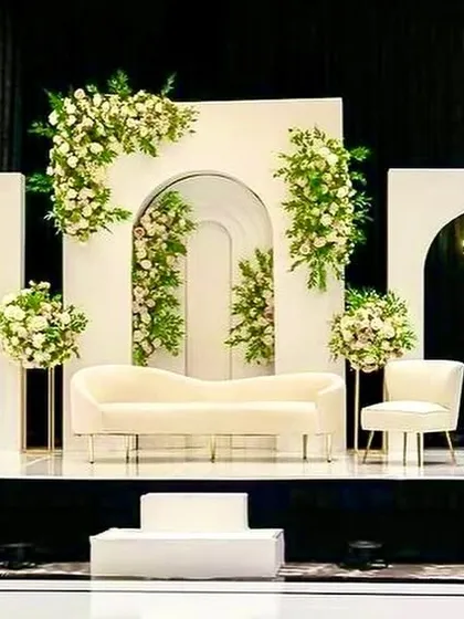 Simple, clean, and elegant. This reception stage proves that minimalism can be magnificent, with white-on-white decor, clean architectural lines, and tasteful green floral garlands.