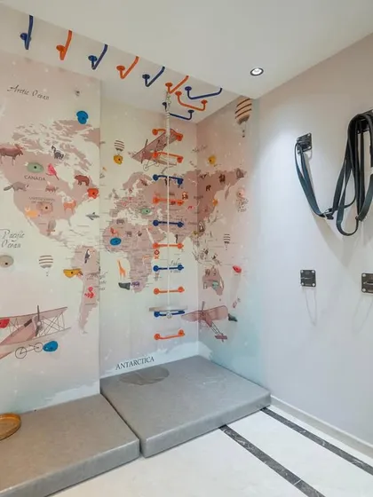 We transformed a corner of this home into a fun and active play zone for the kids. The wall features a world map mural and a climbing ladder with safety mats below, encouraging adventure and physical activity in a safe, indoor environment.