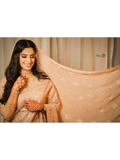 A wide-format shot that lets the bride's smile and the delicate fabric of her dupatta shine. This is a simple yet incredibly elegant bridal portrait.