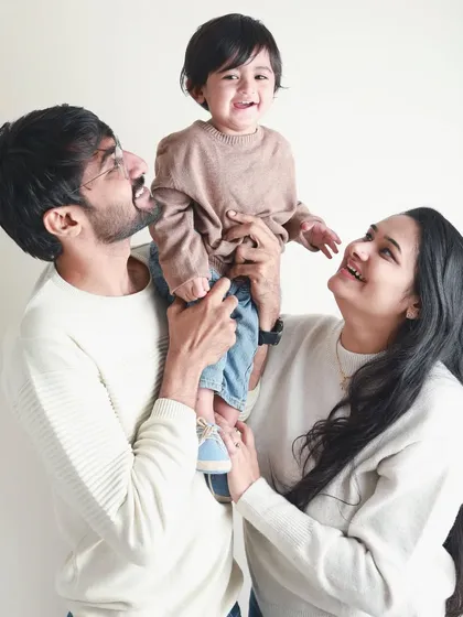 Looking up with love. This family portrait is all about shared joy, with the parents' happy faces reflecting the delight of their child.