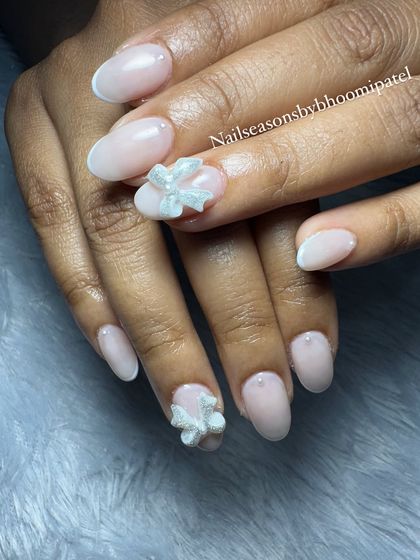 An elegant and delicate nude set with a subtle white French tip, pearl accents, and a stunning 3D bow.