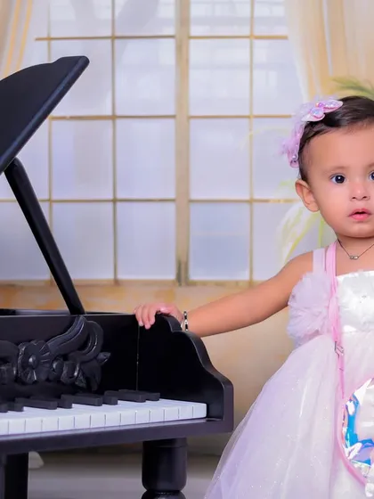 A beautiful close-up portrait of the baby girl by the piano. Her direct gaze and adorable expression make this a captivating image.