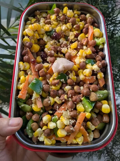 A healthy and colorful lunchbox salad with chickpeas, corn, carrots, and capsicum. Eating food that is close to nature is a celebration every day.