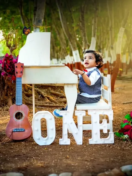 A magical outdoor first birthday shoot. The lighting and natural forest background give this classic piano setup a dreamy, fairytale quality.