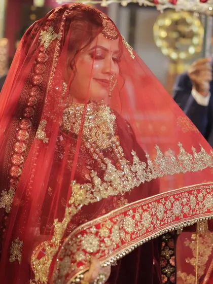 The bride's face, softly veiled by her dupatta. This shot captures the traditional essence of an Indian bride, with her makeup subtly glowing through.