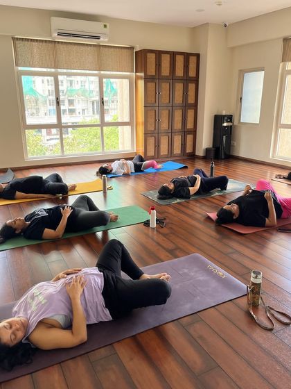 A wide view of the studio during final relaxation. Each woman is in her own space, yet there is a shared energy of peace and surrender that fills the room.