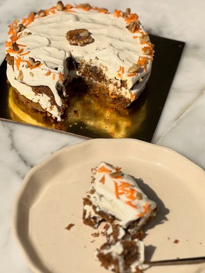 A whole view of our delicious and healthy carrot cake, with a slice cut out to show the moist, spiced interior.