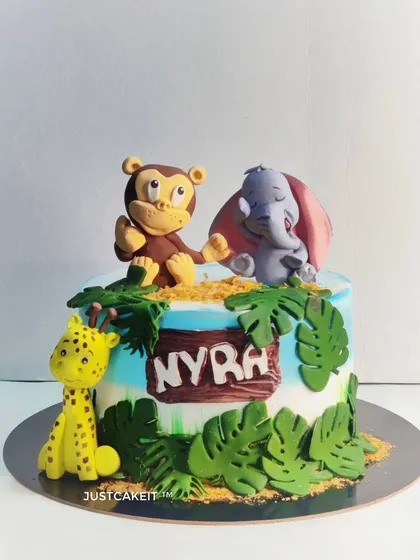 A fun jungle theme cake with a mixed fruit flavor inside. I crafted these cute edible animal figures, including a monkey, elephant, and giraffe, to bring the wild theme to life.