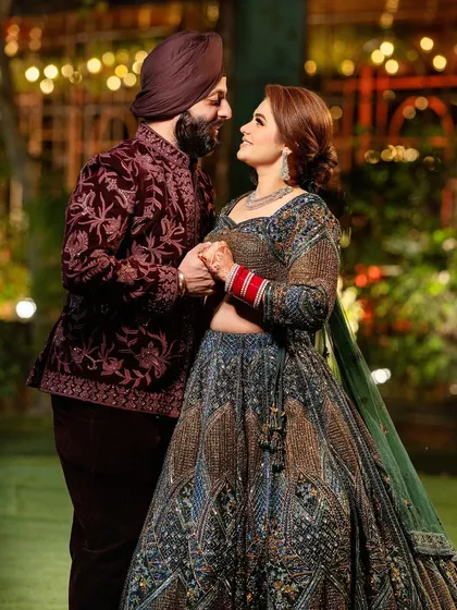 A classic couple pose against a beautifully lit backdrop. This shot highlights their coordinated outfits and the romantic ambiance of their sangeet night.