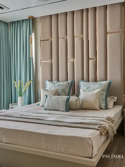 A statement headboard can transform a room. This floor-to-ceiling upholstered design features metallic inlays, adding a touch of glamour that complements the soft blue and beige color scheme.