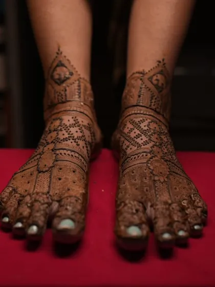 The completed bridal feet design, with fresh henna paste. The pattern is symmetrical and covers the feet beautifully, ready for the wedding festivities.