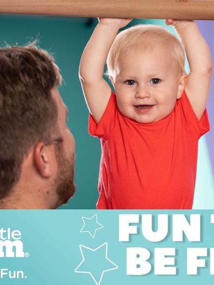 That happy smile says it all. With a parent's help, even the youngest babies can enjoy activities like hanging from the bar, which helps develop their grip strength and body awareness in a fun and secure way.