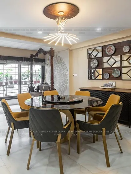 The dining area of the duplex from image 112, featuring a round table, a traditional swing, and a mirrored wall art installation.
