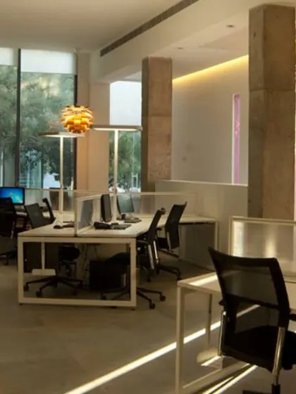 The interior of an experience center I designed in Delhi. The space blends functionality with elegance, featuring exposed concrete pillars, abundant natural light, and clean, modern workstations.