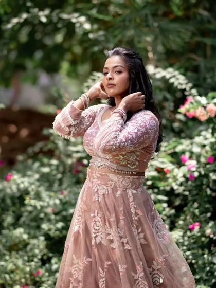 A model posing in a pink lehenga, with a focus on her beautiful, flowing hair and subtle makeup.