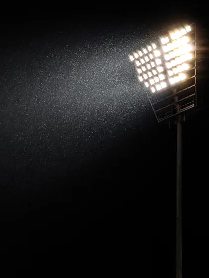 Even rain can't stop the game. A stadium floodlight cuts through the downpour, an atmospheric shot that captures the challenging conditions of a match.