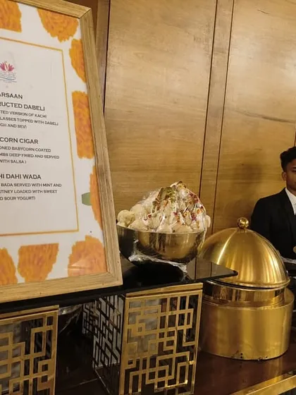 My buffet setups are designed to be both beautiful and informative. Here, a well-lit station features a clear menu listing innovative dishes like Deconstructed Dabeli and Shahi Dahi Wada.