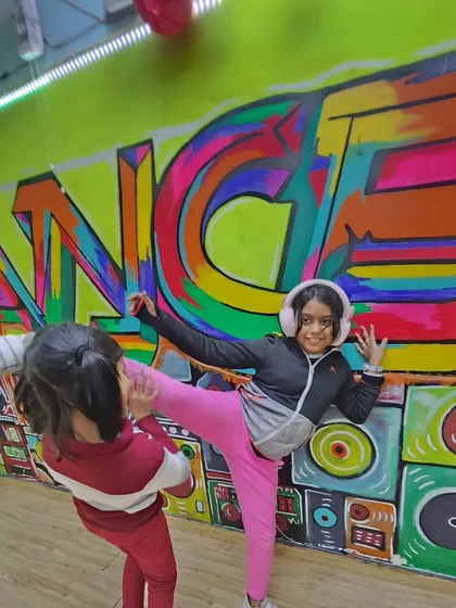 Stretching can be fun too. Our young dancers help each other with leg holds and kicks, building both flexibility and teamwork in the process.