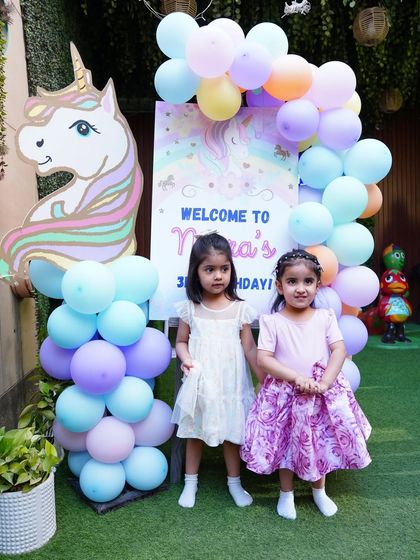 Guests arriving at a unicorn-themed party, greeted by a beautiful pastel balloon garland and a unicorn cutout.