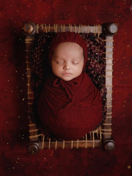 A touch of tradition with this miniature charpai. The rich red wrap and background create a warm and vibrant portrait, celebrating our cultural roots.