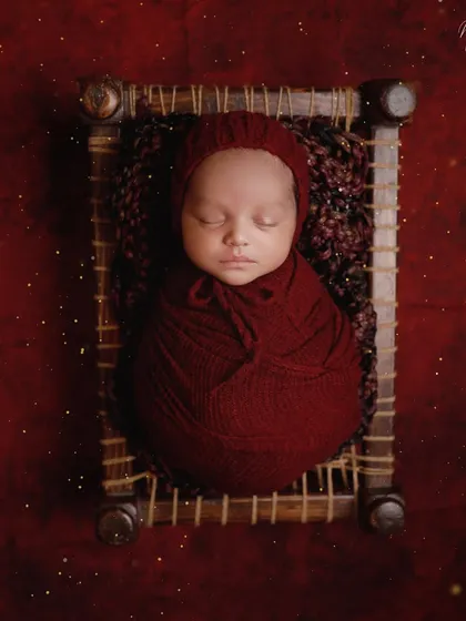 A touch of tradition with this miniature charpai. The rich red wrap and background create a warm and vibrant portrait, celebrating our cultural roots.